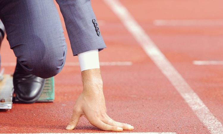 Persona sulla linea di partenza di una pista di atletica, a simboleggiare idealmente la ripresa.